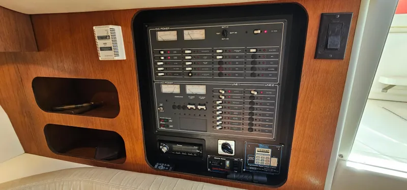 Slide: The Image of Electrical panel of a 1994 Tiara Yachts 3100 Open, featuring control switches and wooden trim. - 33