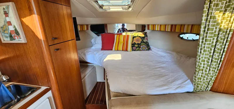 Slide: The Image of 1994 Tiara Yachts 3100 Open cabin with bed, colorful pillows, and wooden cabinetry. - 34