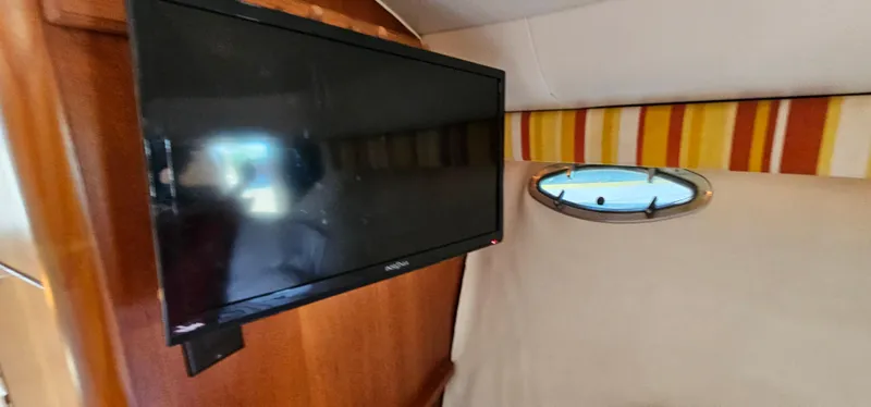 Slide: The Image of Flat-screen TV inside 1994 Tiara Yachts 3100 Open, with wood paneling and porthole window. - 36