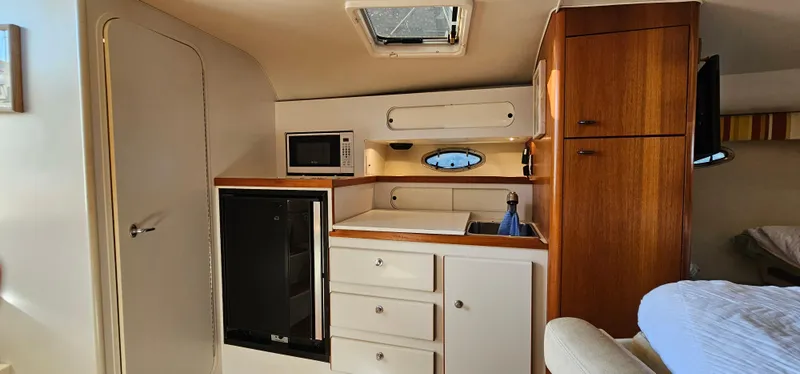 Slide: The Image of 1994 Tiara Yachts 3100 Open cabin interior with kitchenette and wood cabinetry. - 38