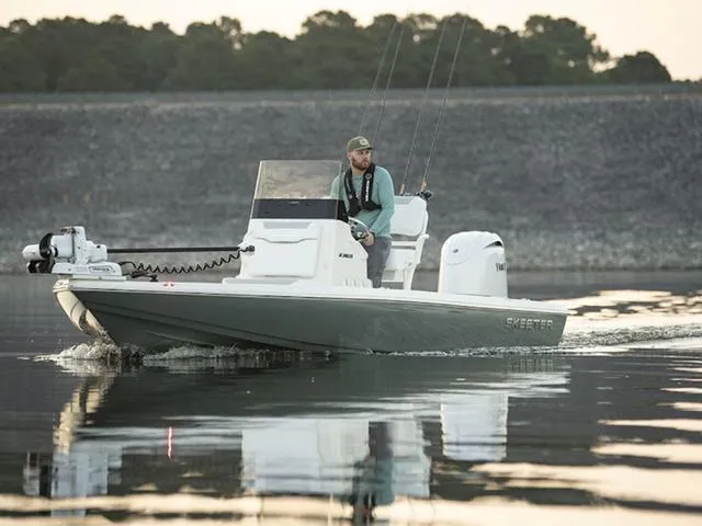 Slide: The Image of 2025 Skeeter SX221 boat cruising on calm water with a person onboard. - 1