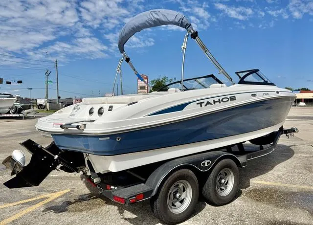 Slide: The Image of 2023 Tahoe 210 Si boat on trailer, blue and white design, parked outdoors under clear sky. - 7