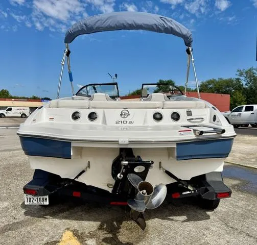 Slide: The Image of 2023 Tahoe 210 Si boat with blue canopy, parked outdoors on a sunny day. - 8