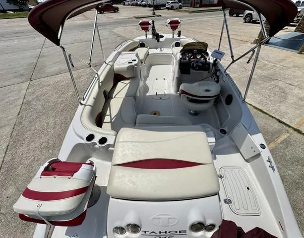 Slide: The Image of 2014 Tahoe 215 Xi boat with spacious seating and canopy, docked on concrete surface. - 10