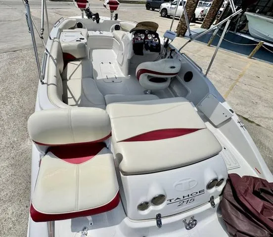 Slide: The Image of 2014 Tahoe 215 Xi boat with white and red seating, docked at a marina. - 11