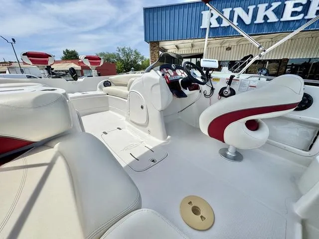 Slide: The Image of 2014 Tahoe 215 Xi boat interior with white and red seating, steering console, and outdoor setting. - 18