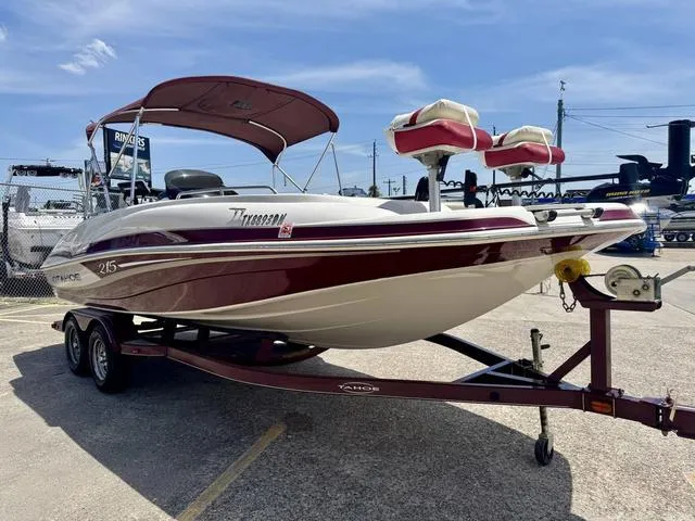 Slide: The Image of 2014 Tahoe 215 Xi boat on trailer, maroon and white, parked outdoors under blue sky. - 5