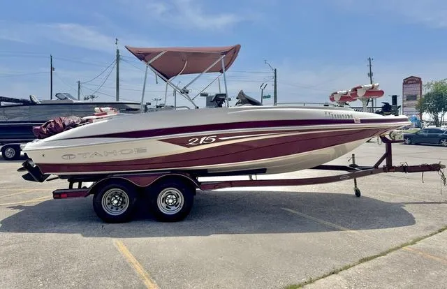 Slide: The Image of 2014 Tahoe 215 Xi boat on trailer, parked in a lot under clear skies. - 6