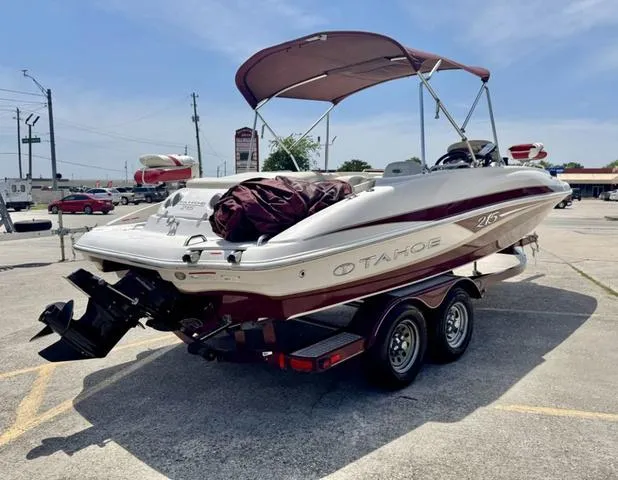 Slide: The Image of 2014 Tahoe 215 Xi boat on trailer with canopy, parked in a lot under clear skies. - 7