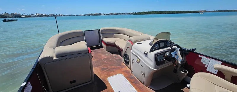 Slide: The Image of 2017 South Bay 500 pontoon boat interior on calm water, featuring comfortable seating and steering console. - 18
