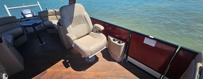Slide: The Image of 2017 South Bay 500 pontoon boat interior with beige seating and wood flooring on water. - 4