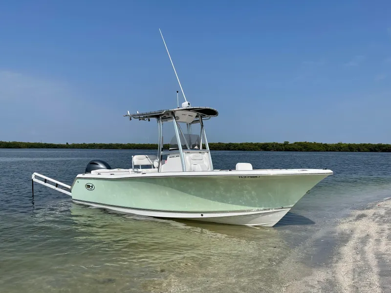 Slide: The Image of 2017 Sea Hunt 225 Ultra boat with trailer, docked on a sandy shore. - 0