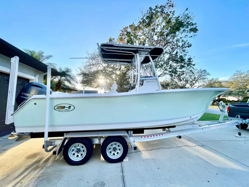 Slide: The Image of 2017 Sea Hunt 225 Ultra boat on 2021 trailer, parked in driveway, sunny day. - 1