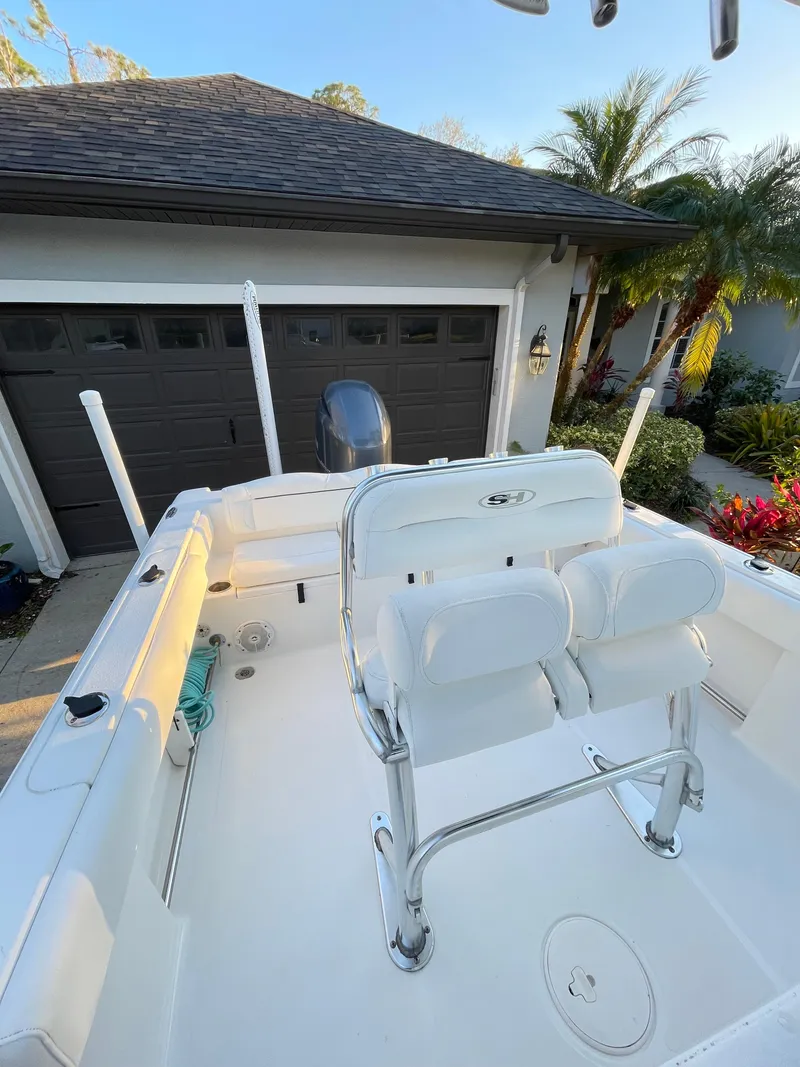 Slide: The Image of 2017 Sea Hunt 225 Ultra boat with dual seats, parked near a garage, palm trees in background. - 18