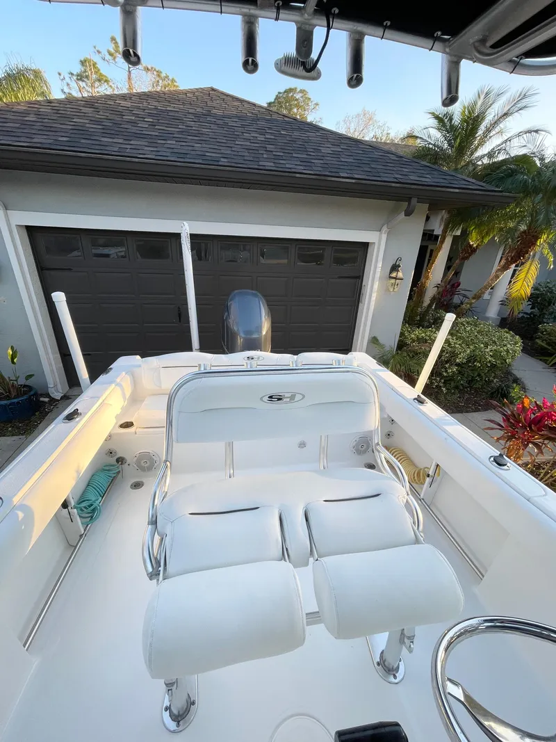 Slide: The Image of 2017 Sea Hunt 225 Ultra boat with dual seats, parked near a garage. - 19