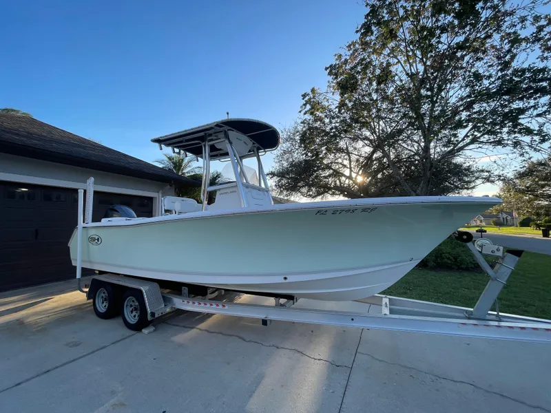 Slide: The Image of 2017 Sea Hunt 225 Ultra boat on trailer, parked in driveway, with trees in background. - 2