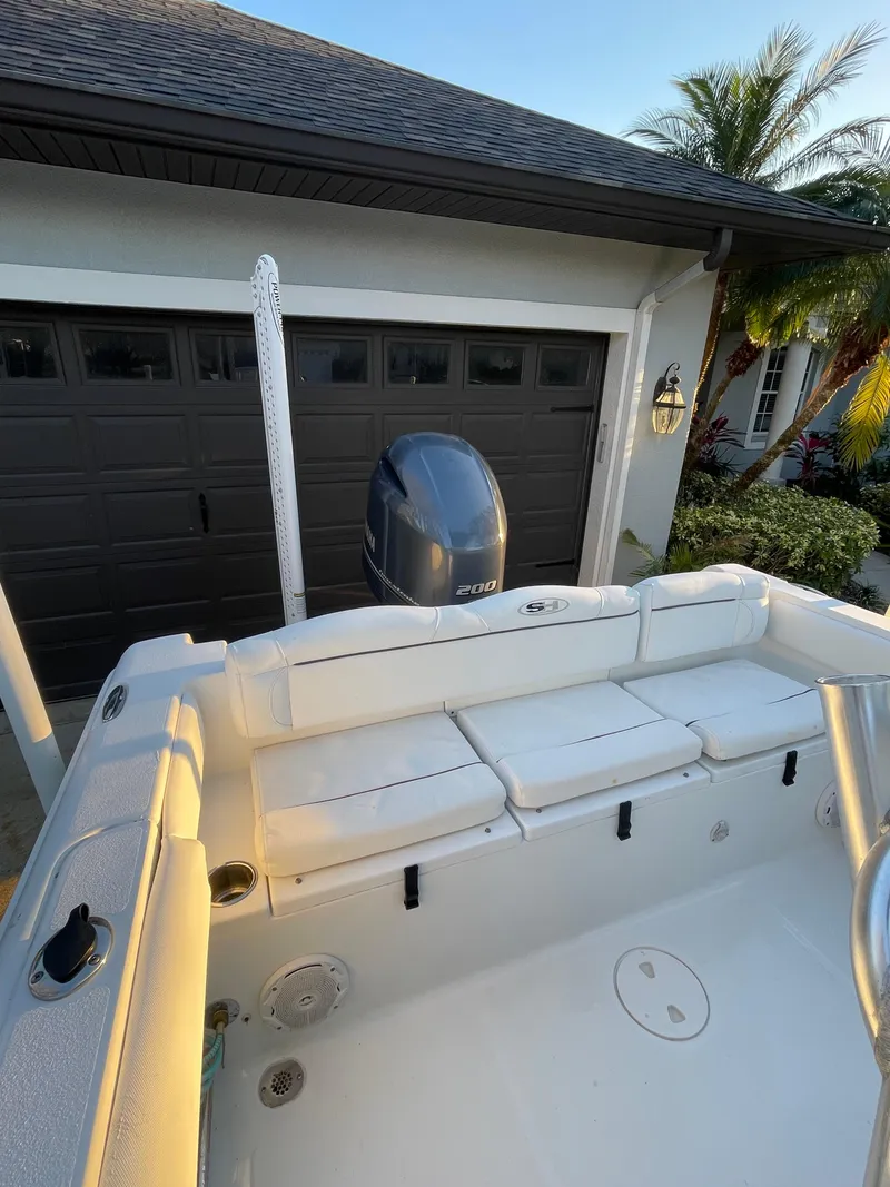 Slide: The Image of 2017 Sea Hunt 225 Ultra boat with outboard motor, parked near a garage. - 21
