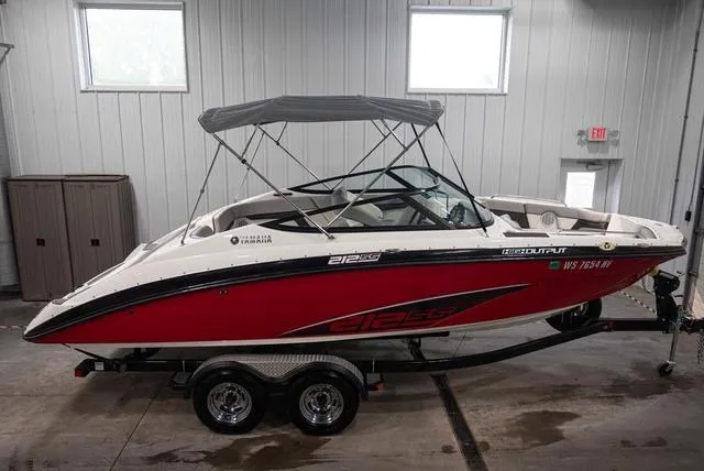 Slide: The Image of 2012 Yamaha Boats 212SS, red and white, parked indoors on a trailer. - 1