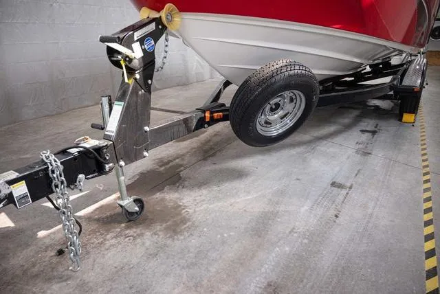 Slide: The Image of 2012 Yamaha Boats 212SS on trailer in garage, red hull visible. - 14