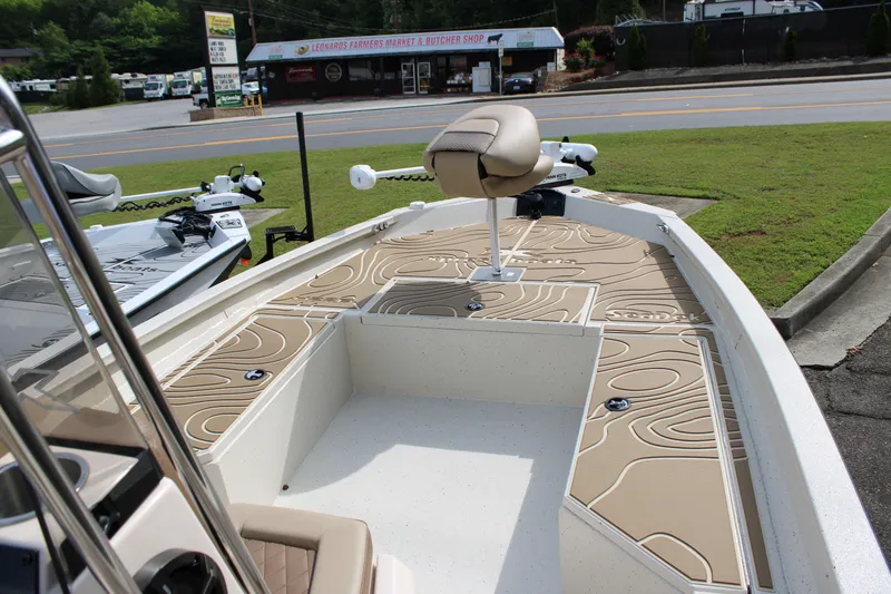 Slide: The Image of 2025 Xpress H22B boat with beige deck, parked near a road and store. - 3