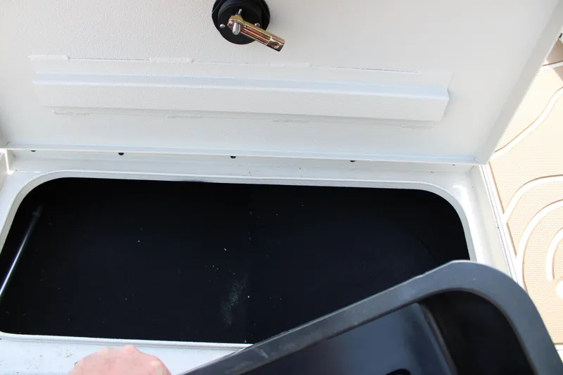 Slide: The Image of Open storage compartment in 2025 Xpress H22B boat, featuring a black interior and latch. - 6