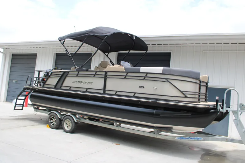 Slide: The Image of 2025 Starcraft SLS-3 Q DH pontoon boat on trailer, parked outside a garage. - 1