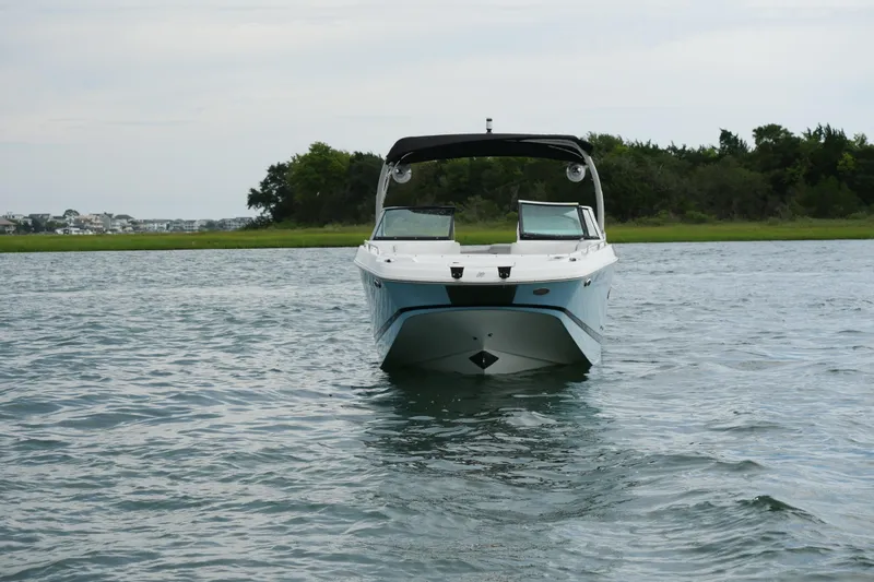 Slide: The Image of 2022 Four Winns HD5 OB boat on calm water with lush green shoreline. - 11