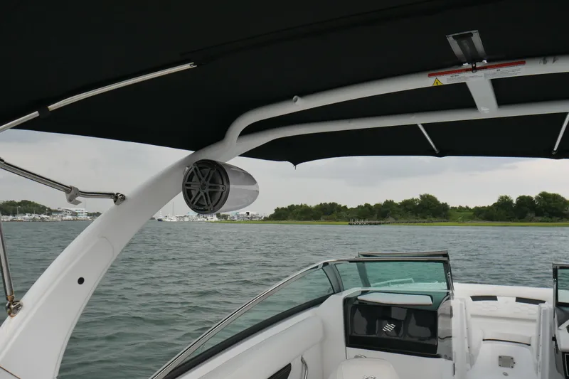 Slide: The Image of 2022 Four Winns HD5 OB boat interior with canopy and speaker, overlooking calm waters. - 24