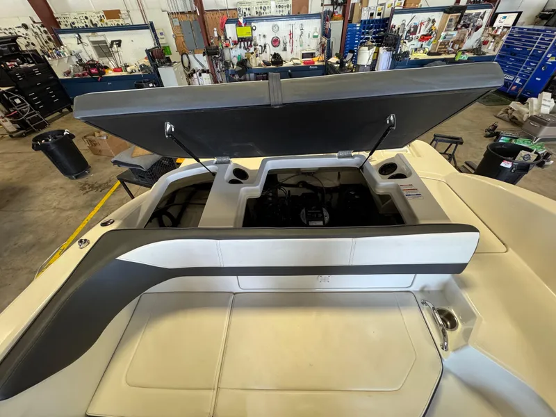 Slide: The Image of 2015 Sea Ray 190 Sport boat engine compartment open in a workshop setting. - 9