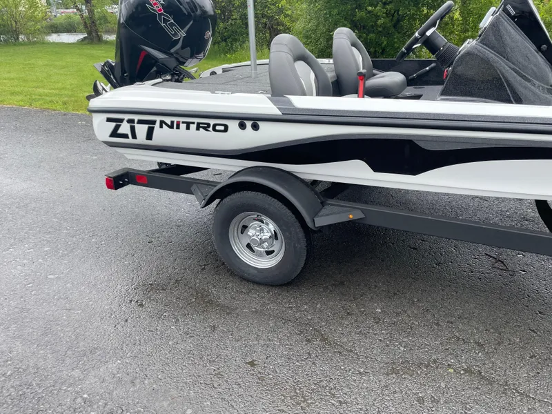 Slide: The Image of 2025 Nitro Z17 boat on trailer, parked on asphalt near grassy area. - 2