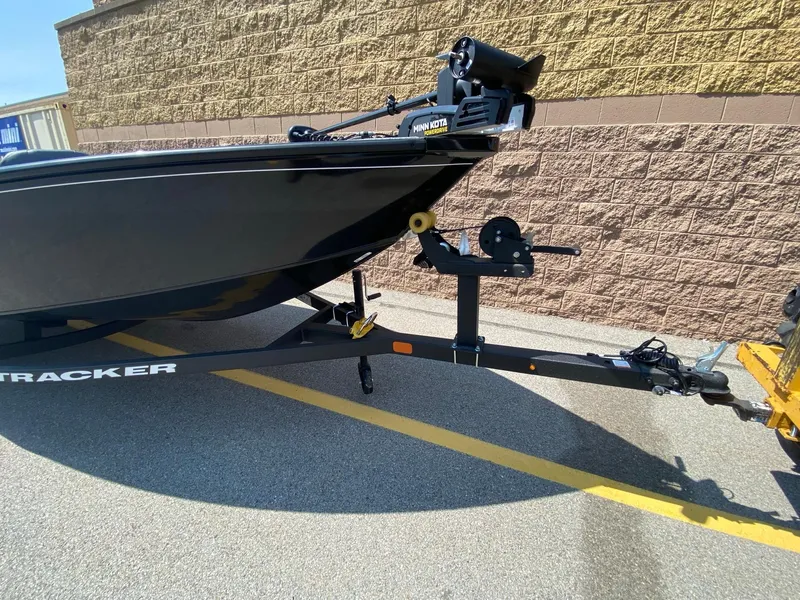 Slide: The Image of 2025 Tracker Super Guide V-16 T boat on trailer, parked by a brick wall. - 2