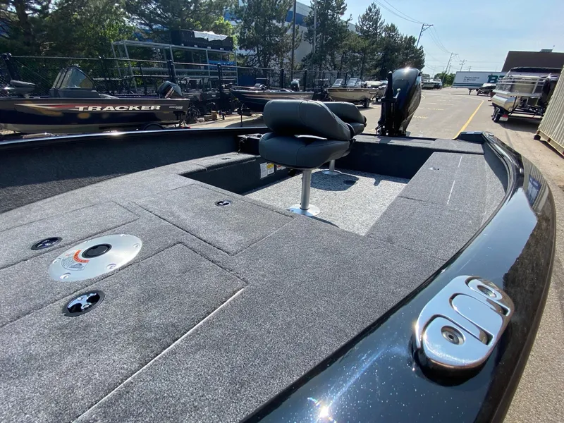 Slide: The Image of 2025 Tracker Super Guide V-16 T boat with seating and storage, parked outdoors. - 5