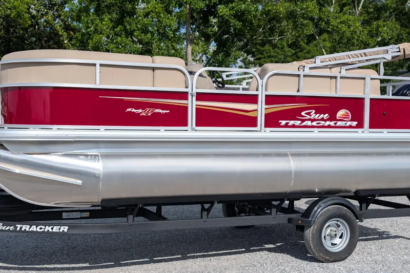 The Image of 2025 Sun Tracker Party Barge 18 DLX pontoon boat on trailer, red and beige design. - 0
