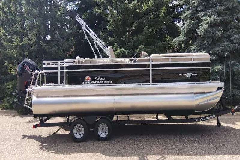 The Image of 2025 Sun Tracker SportFish 22 DLX pontoon boat on trailer, parked outdoors. - 0
