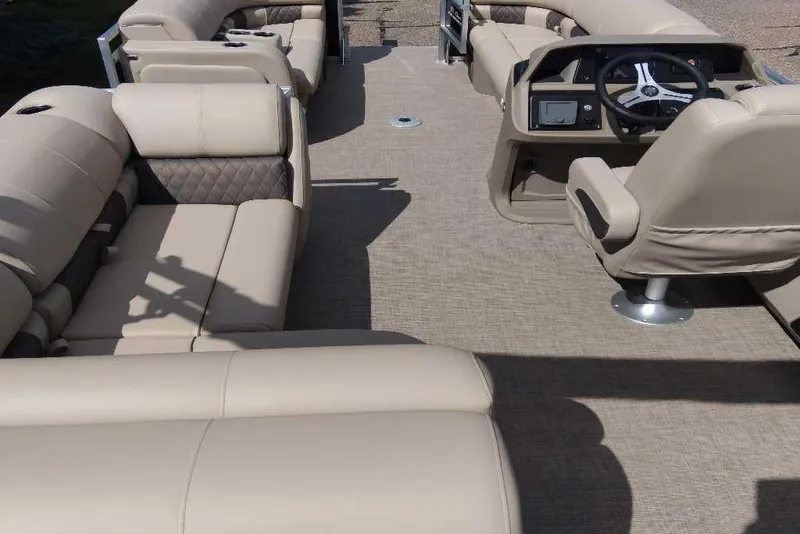 Slide: The Image of 2025 Sun Tracker SportFish 22 DLX pontoon boat interior with beige seating and steering console. - 3