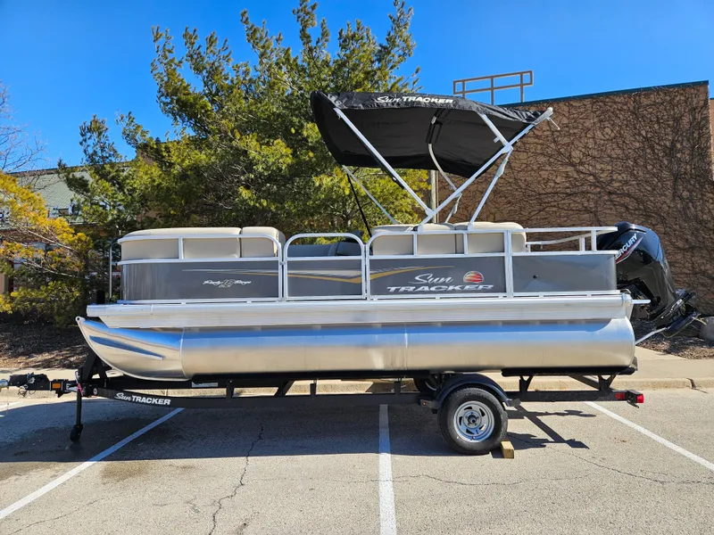 The Image of 2025 Sun Tracker Party Barge 18 DLX pontoon boat on trailer, parked outdoors. - 0