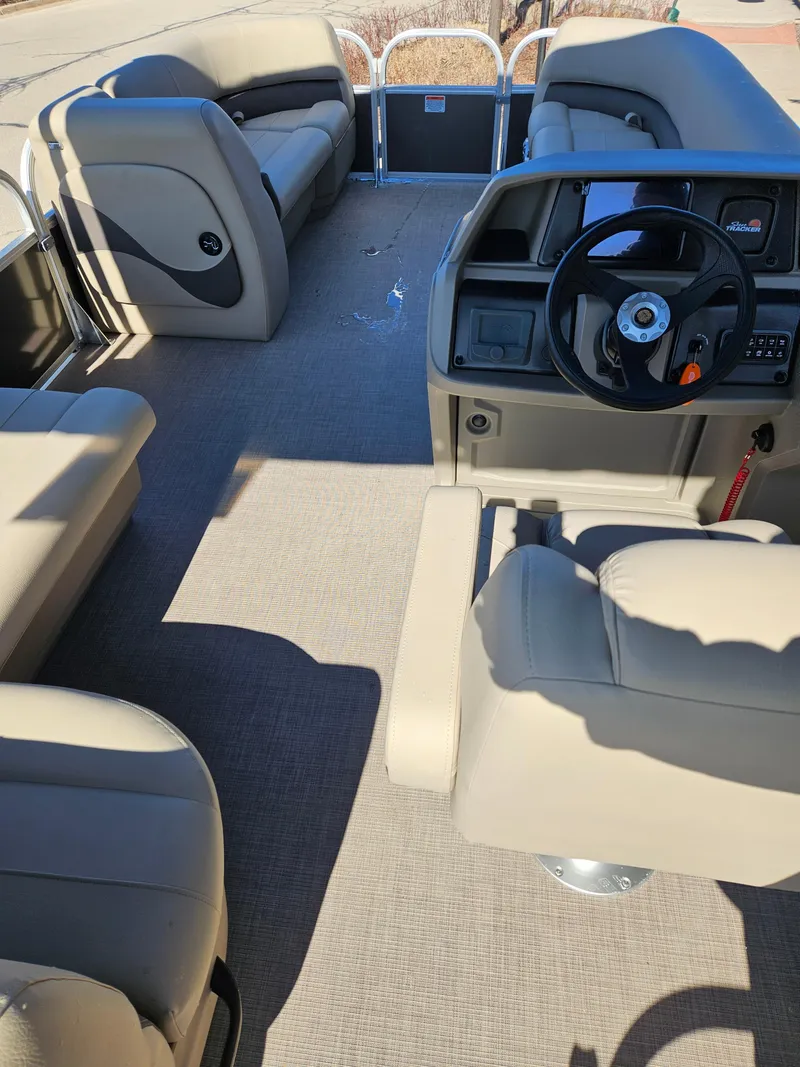 Slide: The Image of 2025 Sun Tracker Party Barge 18 DLX interior with beige seating and steering console. - 3