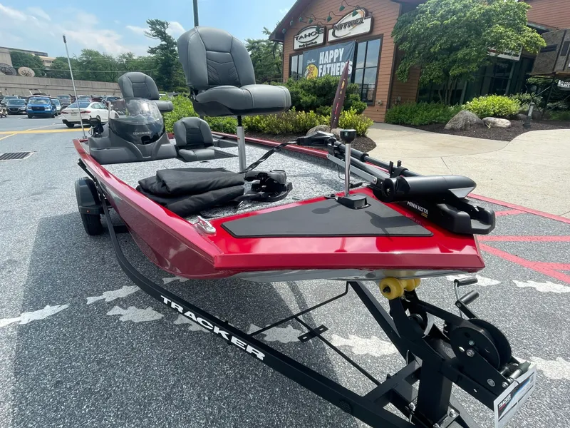 Slide: The Image of 2025 Tracker Pro 170 boat on trailer, parked outside a store, featuring red exterior and seating. - 2