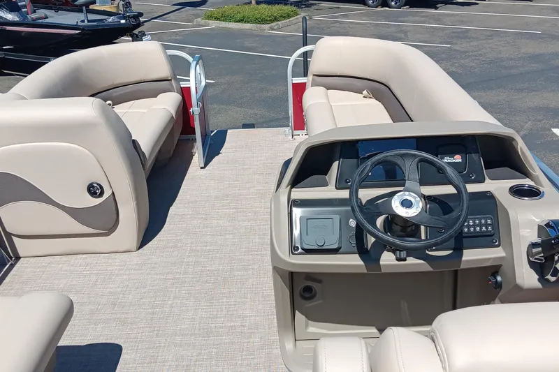 Slide: The Image of 2025 Sun Tracker Party Barge 18 DLX interior with beige seating and steering console. - 3