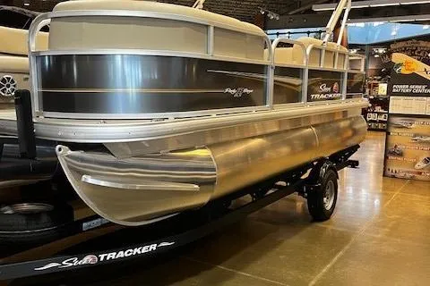 The Image of 2025 Sun Tracker Party Barge 18 DLX pontoon boat displayed indoors on a trailer. - 0