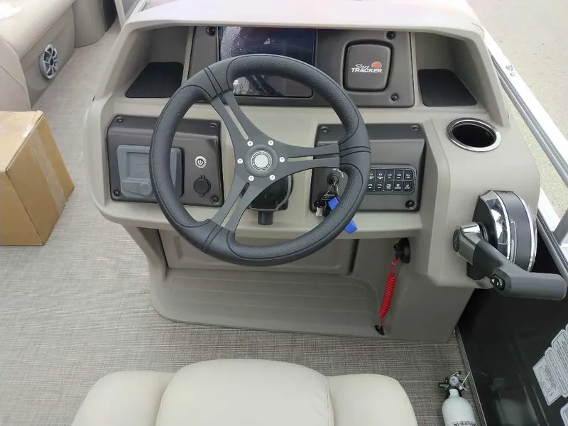 Slide: The Image of 2025 Sun Tracker Party Barge 20 DLX steering console with controls and cup holder. - 2