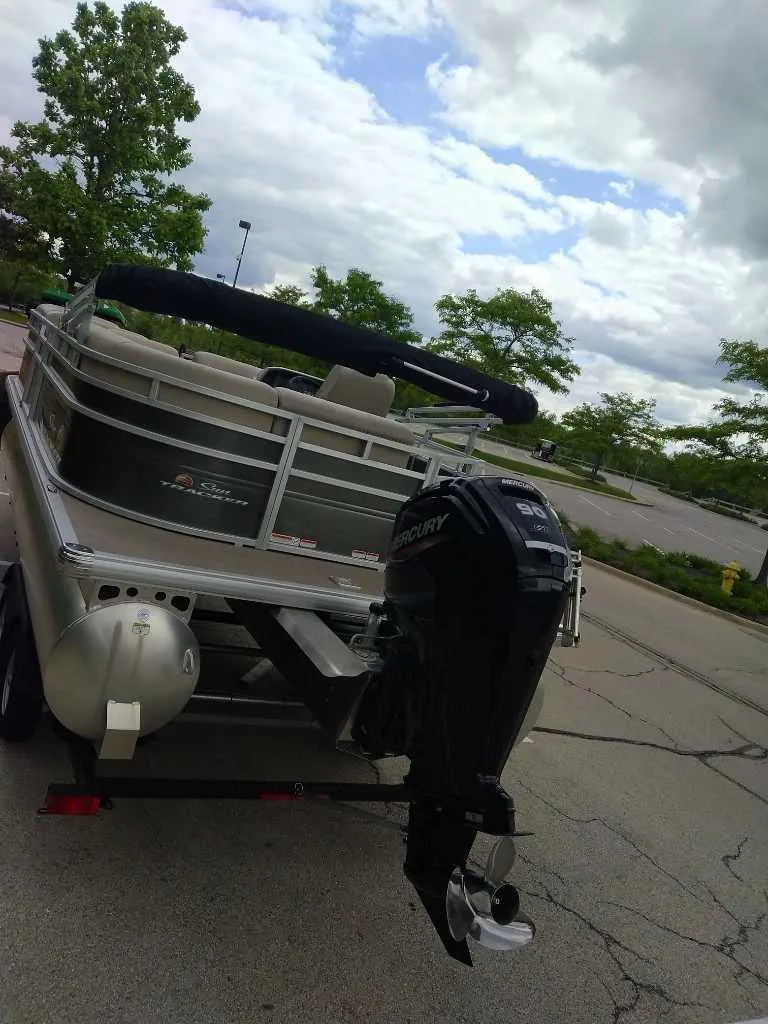 Slide: The Image of 2025 Sun Tracker Party Barge 20 DLX pontoon boat with outboard motor in a parking lot. - 4