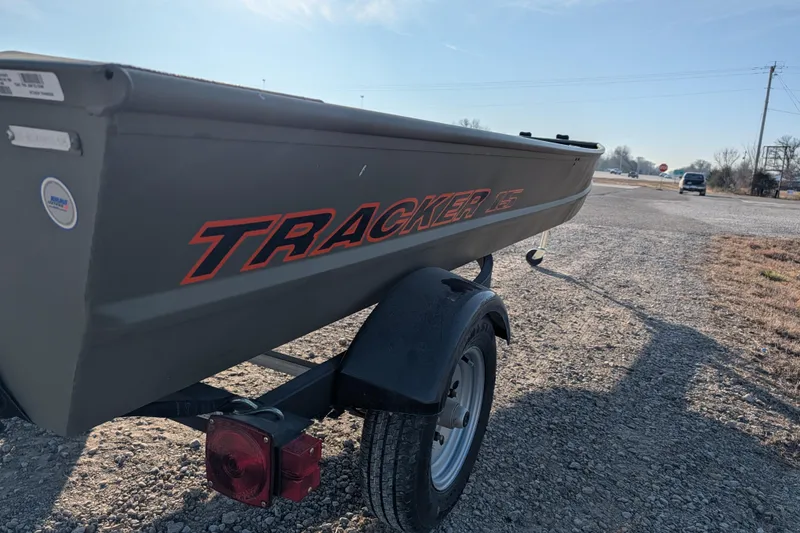 Slide: The Image of 2025 Tracker Grizzly 15 Jon boat on trailer, parked on gravel road. - 23