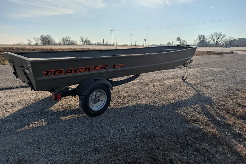 Slide: The Image of 2025 Tracker Grizzly 15 Jon boat on trailer, parked on gravel road. - 24