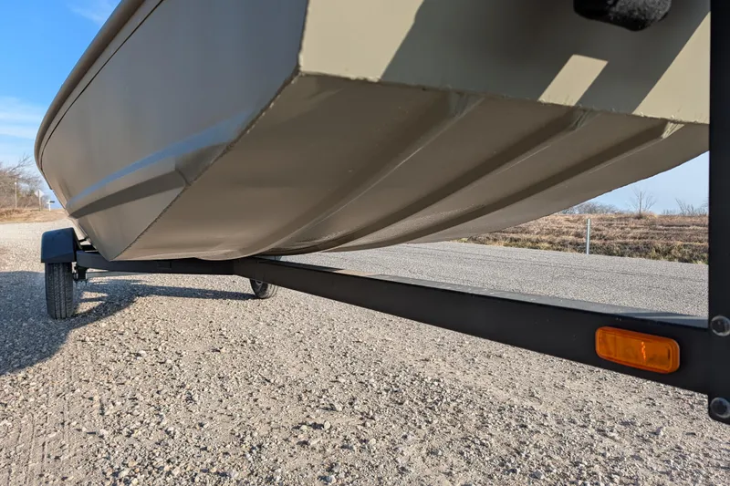 Slide: The Image of 2025 Tracker Grizzly 15 Jon boat on trailer, gravel road background. - 27