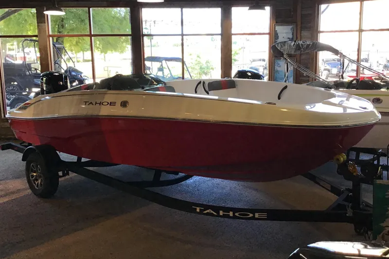 The Image of 2025 Tahoe T18 boat in showroom, red and white design on trailer. - 0