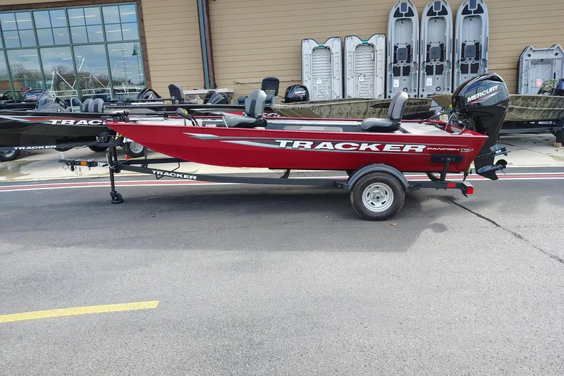 The Image of 2025 Tracker Panfish 17 boat in red, displayed on a trailer outside a showroom. - 0