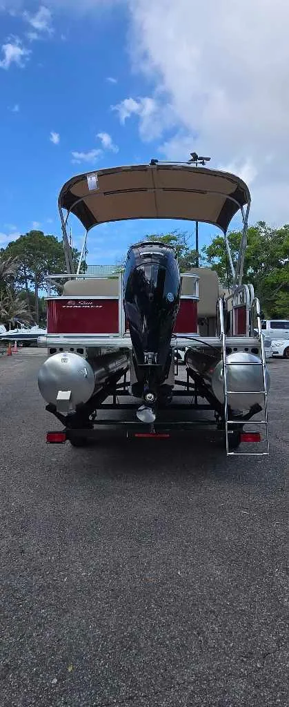 Slide: The Image of 2025 Sun Tracker Bass Buggy 16 XL Select pontoon boat, rear view, parked outdoors. - 3