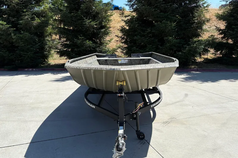 Slide: The Image of 2025 Tracker Grizzly 2072 Utility boat on trailer, parked outdoors with trees in background. - 4