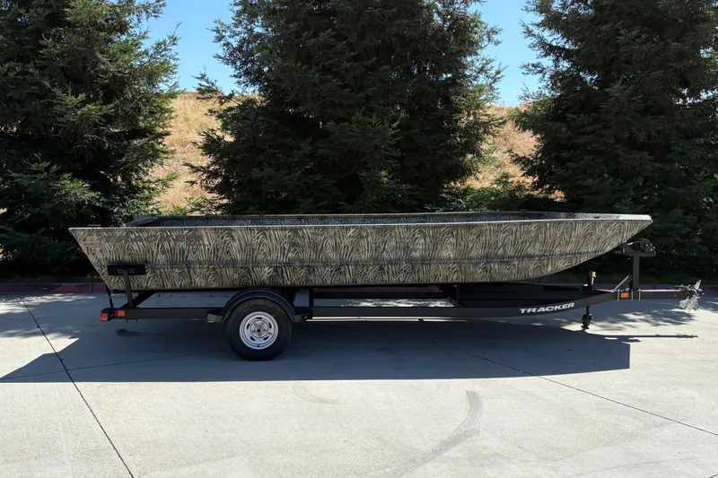 Slide: The Image of 2025 Tracker Grizzly 2072 Utility boat on trailer, parked outdoors near trees. - 6
